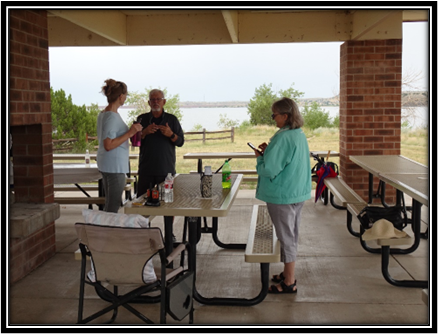 A group of people standing around a picnic table

Description automatically generated