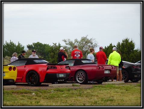 A group of people standing around a red car

Description automatically generated