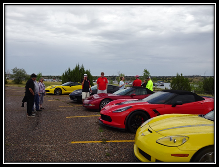 A group of people standing in a parking lot with cars

Description automatically generated