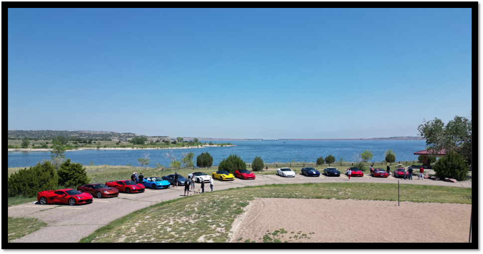 Cars parked on a road next to a body of water

Description automatically generated