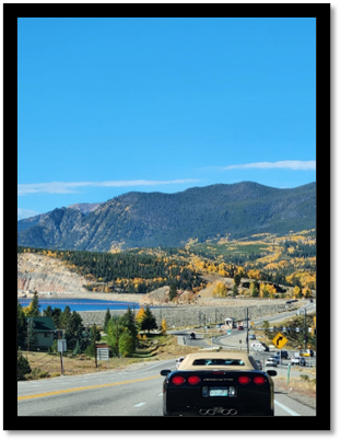 A road with cars and mountains in the background

Description automatically generated