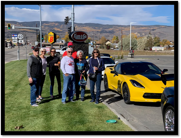 A group of people standing in front of a yellow sports car

Description automatically generated