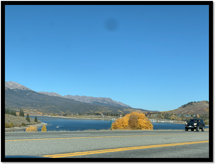 A road with a lake and mountains in the background

Description automatically generated