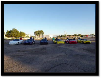 A group of cars parked on a dirt lot

Description automatically generated