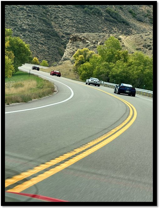 Cars on a road with trees and hills

AI-generated content may be incorrect.