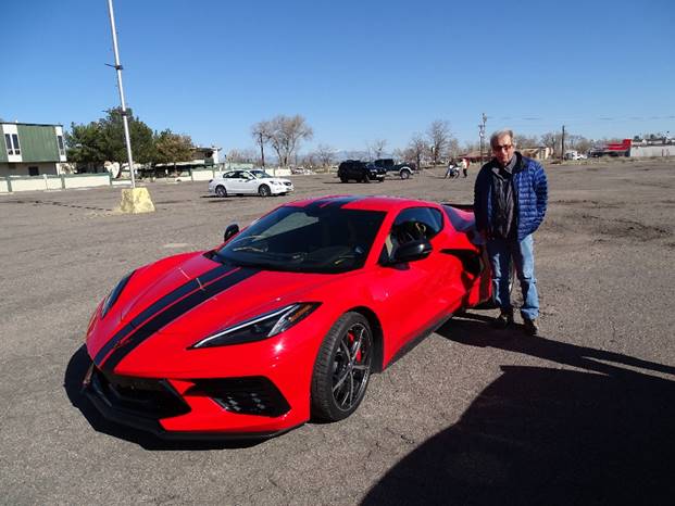 A person standing next to a red sports car

Description automatically generated