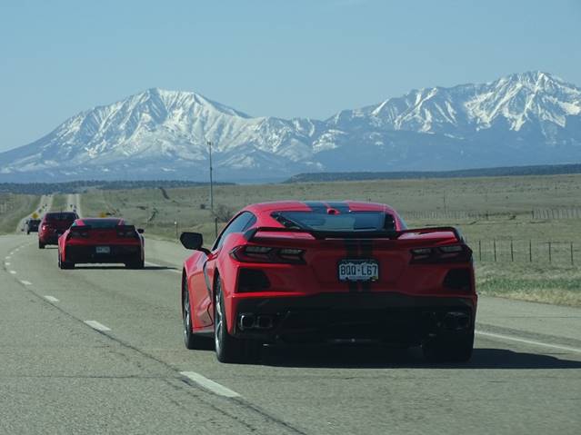 A red sports car on a road with mountains in the background

Description automatically generated with medium confidence