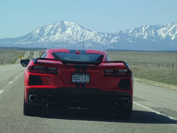 A red sports car parked on a road with mountains in the background

Description automatically generated with medium confidence