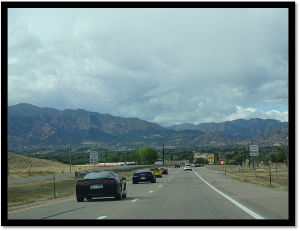 A group of cars driving down a road with mountains in the background

Description automatically generated with medium confidence