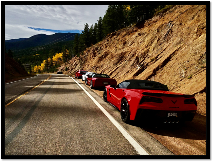 A group of red sports cars parked on a road

AI-generated content may be incorrect.