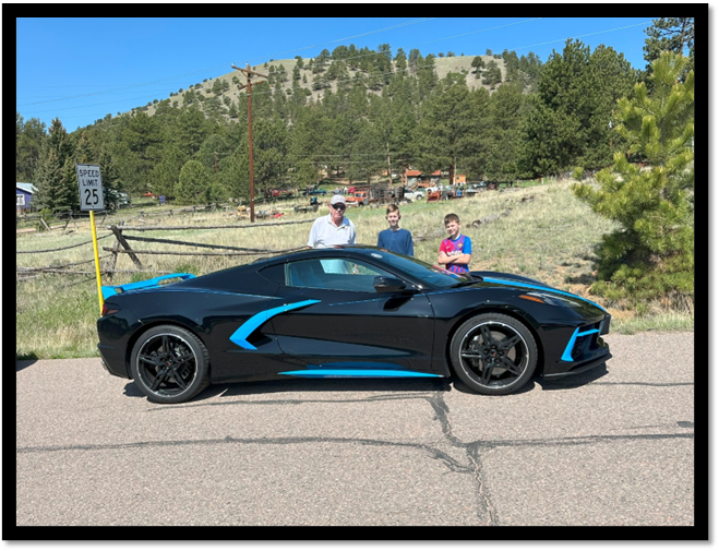 A black sports car with blue stripes and people in the background

AI-generated content may be incorrect.