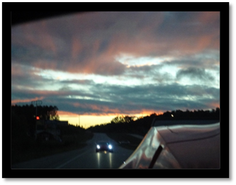 A car driving on a road at sunset

Description automatically generated