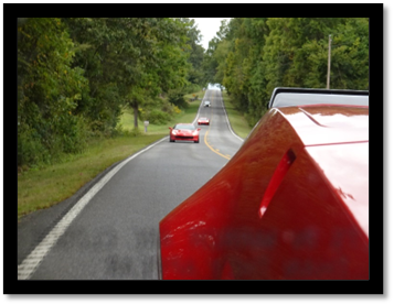 A red sports cars on a road

Description automatically generated