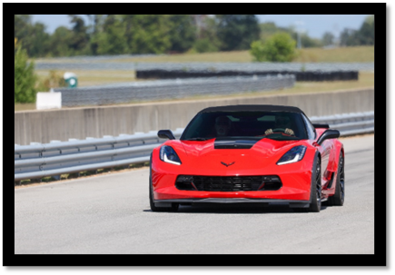 A red sports car on a road

Description automatically generated