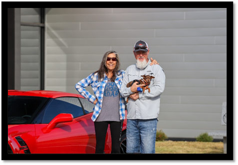 A person and person standing next to a red car

Description automatically generated