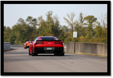 A red sports car on a road

Description automatically generated