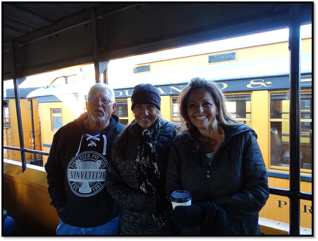 A group of people posing for a photo in front of a train

Description automatically generated with medium confidence