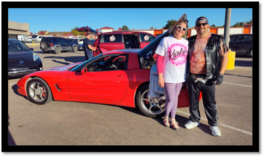 A group of people standing next to a red car

Description automatically generated