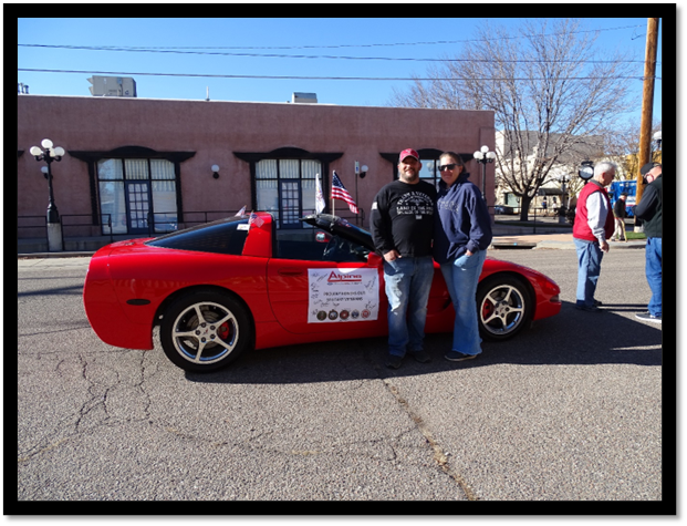 A group of people standing next to a red sports car

Description automatically generated