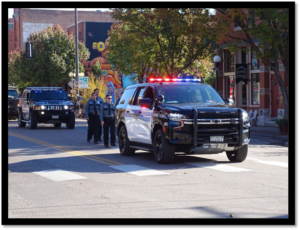 Police officers standing in front of a police car

Description automatically generated