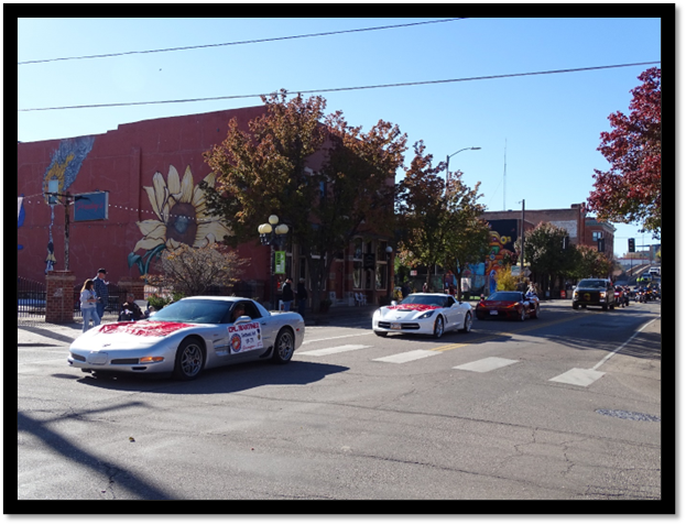 A group of cars driving down a street

Description automatically generated