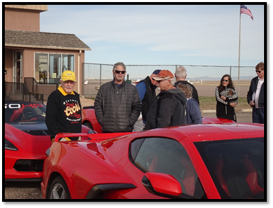 A group of people standing next to a red car

Description automatically generated with medium confidence